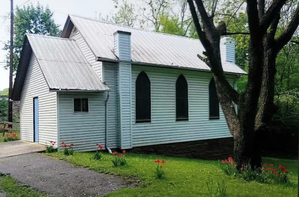 Little Falls Chapel: a small white clapboard chapel with pointed arched windows, a metal roof and red tulips along the lawn, on Foster Dr in Falling Waters, WV