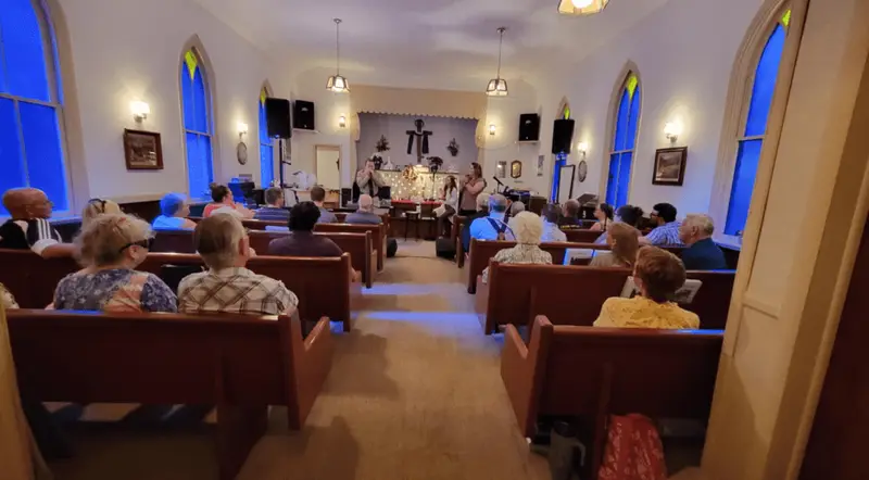 Congregation gathering inside Little Falls Chapel during a service, representing a close-knit community.